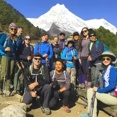 Grupa turystów na tle ośnieżonych gór podczas Manaslu Circuit Trek. Wszyscy uśmiechnięci, gotowi na przygodę.