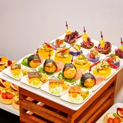 Elegancki catering urodzinowy Warszawa: kolorowe przekąski, sushi, tartaletki i owoce morza na białych talerzykach.