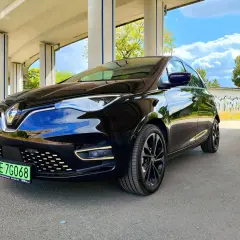 Czarny Renault Zoe błyszczy pod betonowym wiaduktem. Ten elektryczny samochód oferuje imponujący zasięg, idealny na miejskie podróże i dalsze wyprawy.