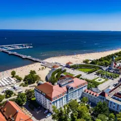 Widok na fajny hotel nad morzem, z plażą pełną ludzi i molo.