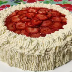 En vacker jordgubbstårta med fluffigt gräddtäcke och ett glansigt jordgubbslager i mitten. Denna ser ut att vara den godaste jordgubbstårtan!