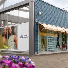 Vero Moda outlet med skyltar som visar "New Store Opening Soon". Blommor i förgrunden.