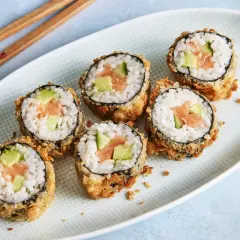 Knuspriges Tempura Sushi mit Lachs und Avocado auf einem Teller, bereit zum Genießen.