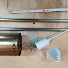 Elementy do samodzielnego złożenia lampy wiszącej: metalowy klosz, żarówka, oprawka i pręty.