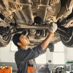 Mécanicien travaillant sous une voiture, vérifiant le dessous. Il pourrait s'agir d'une étape pour savoir comment nettoyer capteur abs.