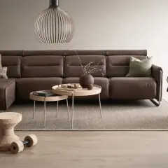 Ein braunes Ledersofa harmoniert perfekt mit der Wandgestaltung in warmen Erdtönen. Welche Wandfarbe passt dazu? Hier eine Inspiration.