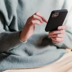 Dłonie trzymające telefon, zastanawiające się, co napisać po kłótni.