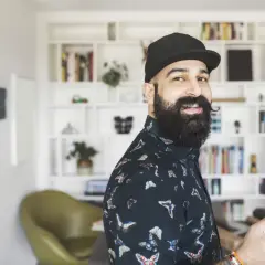 Ein lächelnder Mann mit Bart und Kappe, der als creative director neue Ideen entwickelt.