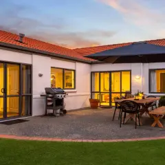 Beautiful house photography showcasing a patio with a BBQ, dining set, and umbrella, ready for entertaining.