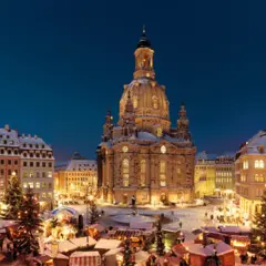 Śnieżny jarmark w Dreźnie. W tle Frauenkirche, po bokach oświetlone kamienice i choinki.