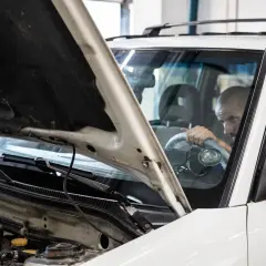 Mechanik sprawdza silnik białego auta. Czy to vaico co to za firma?