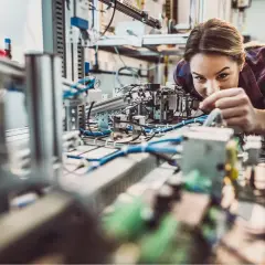 Junge Frau arbeitet konzentriert an einer komplexen Anlage im Bereich IU Elektrotechnik.