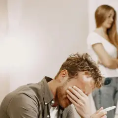 Uomo disperato con test di gravidanza in mano, mentre una donna si volta. Un esempio di uomini che non sanno stare in una relazione.