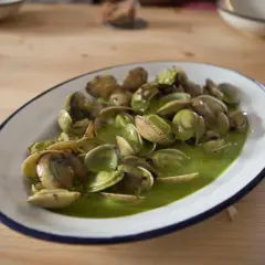 Plato de almejas en salsa verde, un manjar marino bañado en una vibrante y sabrosa salsa.