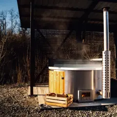 Gorąca para unosi się z jacuzzi, podgrzewanego drewnem. Zastanawiasz się, jak długo nagrzewa się woda w jacuzzi? Czas zależy od wielu czynników.