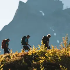 Vandrare på väg mot Kebnekaise från Nikkaluokta, med höstens färger och fjäll i bakgrunden.
