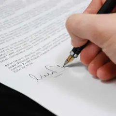 Mano firmando un documento con una pluma estilográfica, un paso clave para firmar contrato online.