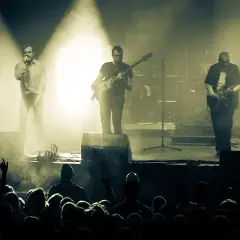 Koncert zespołu Coma z Leszkiem Żukowskim na wokalu. Muzycy na scenie, w tle dym i światła. Publiczność w pierwszym planie.