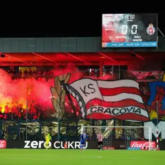 Oprawa kibiców najstarszego klubu piłkarskiego w Polsce, Cracovii, z racami i transparentami. Na tablicy wyników 0:0.