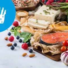 Zdrowa dieta przy łuszczycy: łosoś, warzywa, owoce, orzechy i tofu. Ikona dłoni symbolizuje problemy skórne.