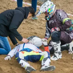 Po wypadku Tomasza Golloba, ratownicy udzielają pomocy leżącemu na piasku zawodnikowi w stroju motocyklowym.