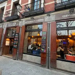 Fachada del restaurante Cava Baja 17, con gente dentro disfrutando de tapas y copas.