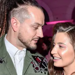 Julia Wieniawa i Baron patrzą na siebie z uśmiechem. On ma dredy i ozdobną kurtkę, ona błyszczące różowe cienie do powiek.