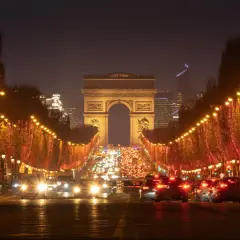 Les Champs-Élysées illuminés pour le réveillon de Noël, avec le trafic parisien et l'Arc de Triomphe en fond.