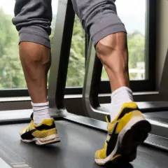 Jambes musclées sur un tapis roulant, mettant en valeur l'exercice mollet.