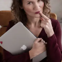 Kobieta z laptopem, z palcem przy ustach, zastanawia się nad zadaniem z angielskiego B1.