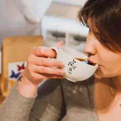 Kobieta popija kawę z filiżanki. Czy kawa wpływa na trzustkę?