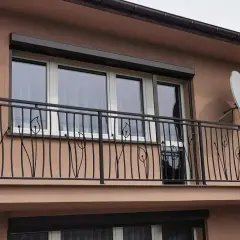 Elegancka, czyszczenie balustrady metalowej z motywem roślinnym. W tle okna i antena satelitarna.