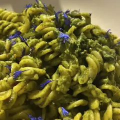 Fusilli-Pasta mit einer cremigen grünen Soße, garniert mit blauen Kornblumen. Ein köstliches italienisches Palmkohl Rezept.