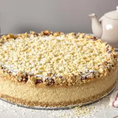 Käsekuchen mit Streuseln und Nüssen, inspiriert von Landfrauen Kuchen Rezepten. Puderzucker bestäubt die Krümel und den Rand.