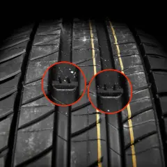 Gros plan sur un pneu de voiture, avec deux cercles rouges mettant en évidence les indicateurs d'usure. C'est un bon indice pour savoir quand changer ses pneus.