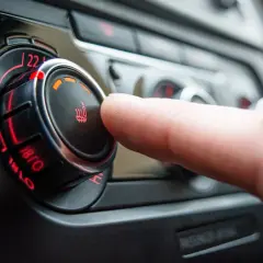 Dedo girando el control de temperatura del coche, pero no funciona la calefacción del coche. El indicador muestra 22 grados.