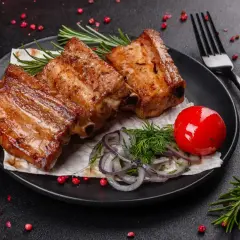 Soczyste żeberka z grilla, podane z pomidorkiem, cebulką i ziołami. Idealne na letni wieczór.