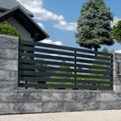 Nowoczesny betonowy płot z poziomymi, ciemnymi przęsłami i betonowymi słupkami.