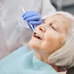 Starsza pani u dentysty, która właśnie otrzymała protezę akronową.