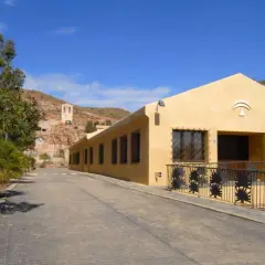 La casa de los volcanes, un edificio amarillo con rejas de palmeras, se alza bajo un cielo azul.