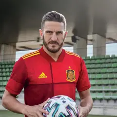 Piłkarz w czerwonej koszulce Hiszpanii z piłką, gotowy do gry w stylu tiki-taka.