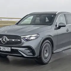 Szary Mercedes GLC 300d na mokrej drodze, z widocznymi kroplami deszczu na karoserii.