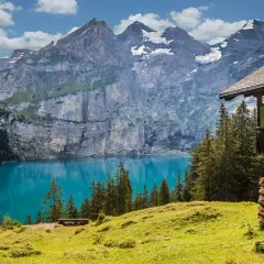 Un rifugio alpino domina un lago turchese, circondato da montagne maestose. Un vero paradiso tra le località di montagna più belle in estate.