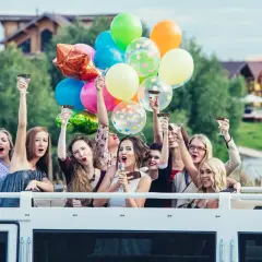 Radosne kobiety z kieliszkami i balonami świętują wieczór panieński.