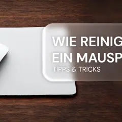 Weiße Maus auf weißem Mauspad, daneben Text: "Wie reinigt man ein Mauspad? Tipps & Tricks".