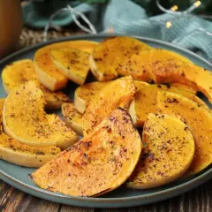 Rodajas de calabaza a la plancha, doradas y sazonadas con hierbas, servidas en un plato azul.