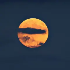 Pomarańczowa pełnia księżyca, częściowo zasłonięta przez ciemną chmurę, przypomina flagę Palau.