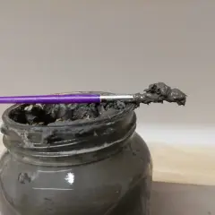 Pinceau violet trempé dans une pâte grise, prête à recoller terre cuite.