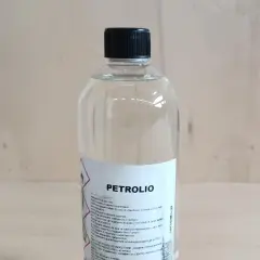 Bottiglia di **petrolio bianco su legno**. Liquido infiammabile, da usare con cautela.