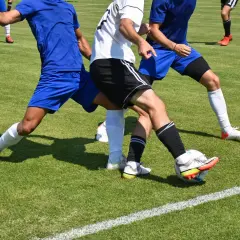 Piłkarze w akcji, jeden próbuje odebrać piłkę, pokazując skuteczną grę defensywną.